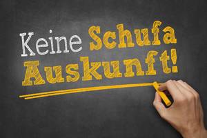 Kredite ohne Schufa im Test: Eine Hand schreibt mit Kreide Text