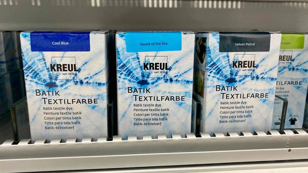 Batikfarben im Test. Verpackungen mit Batikfarben im Regal.