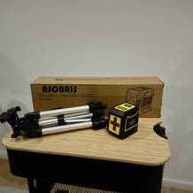 Der Kreuzlinienlaser von Asobris steht neben seiner Verpackung auf einem Rollwagen.