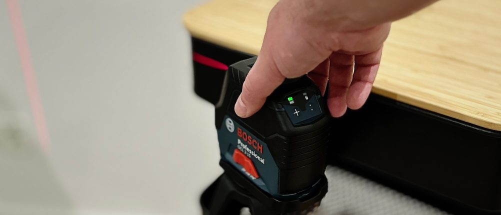 Die magnetische Halterung des Kreuzlinienlasers von Bosch haftet an einem Rollwagen aus Metall.