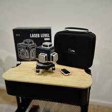 Der Kreuzlinienlaser von Cigman steht neben seiner Verpackung auf einem Rollwagen.