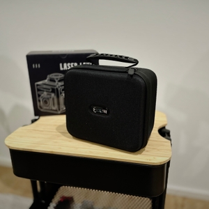 Die Tragetasche des Kreuzlinienlasers von Cigman steht auf einem Rollcontainer.