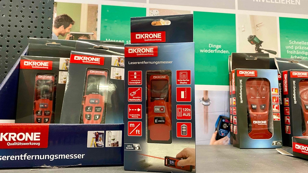 Im Test: Ein verpackter Laser-Entfernungsmesser steht neben anderen Geräten in einem Regal.