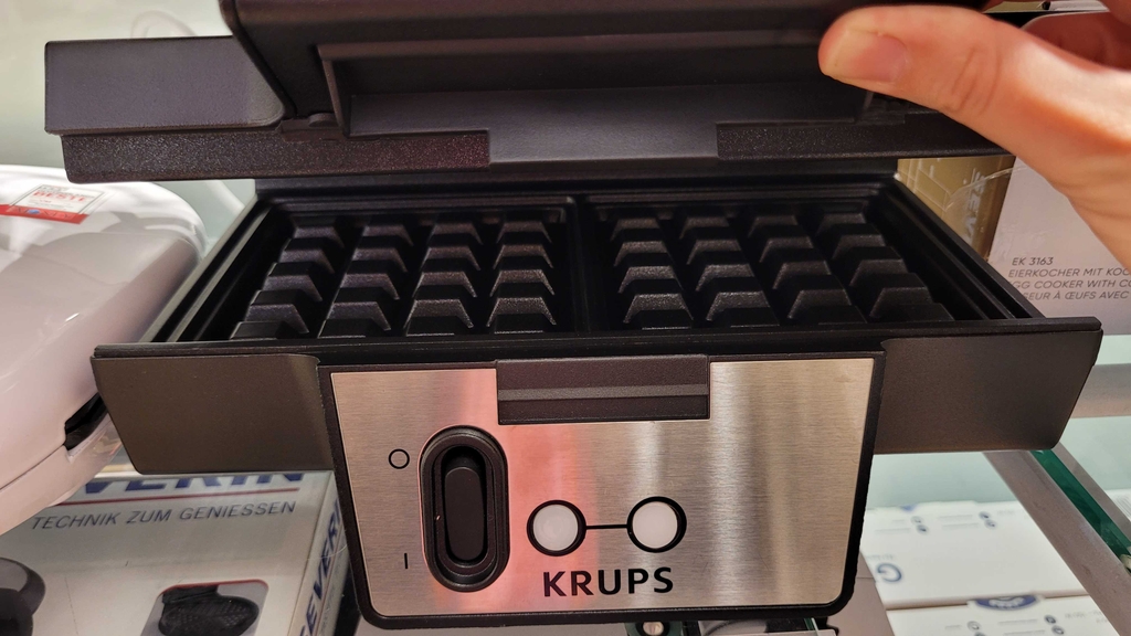 Eine Hand öffnet den Deckel eines getesteten belgischen Waffeleisens.