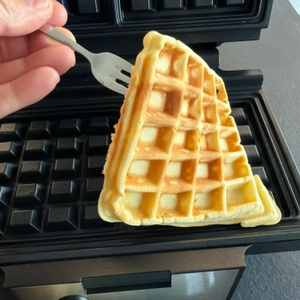 Mit einer Gabel wird eine fertige Waffel aus dem Krups FDK 251 entfernt