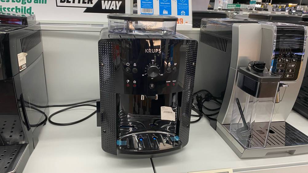 Ein getesteter Kaffeevollautomat bis 300 Euro von vorne zwischen anderen Geräten auf einem Verkaufsregal.