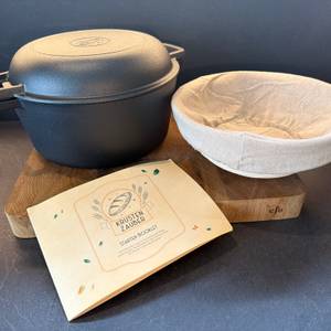 Der Lieferumfang vom Krustenzauber-Gusseisen-Topf steht auf einem Holzbrett