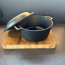 Der Krustenzauber-Gusseisen-Topf steht auf einem Holzbrett