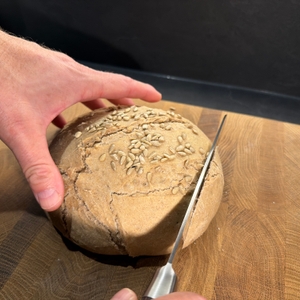 Mit einem Messer wird Brot aus dem Krustenzauber-Gusseisen-Topf geschnitten