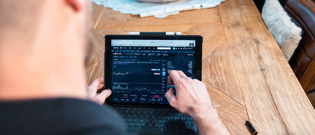 Ein Mann handelt an einem Tablet mit Kryptos.