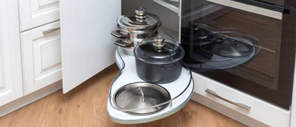 Verschiedene Töpfe in einem ausziehbaren Eckschrank neben dem Herd.