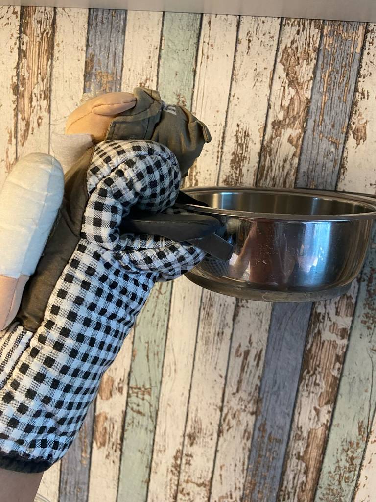 Eine mit dem Küchenhandschuh im Test behandschuhte Hand greift einen Kochtopf am Griff.
