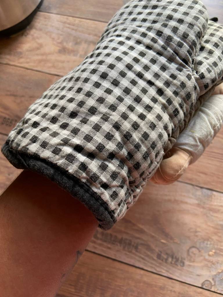 Der karierte Küchenhandschuh im Test ist über eine Hand gestülpt.