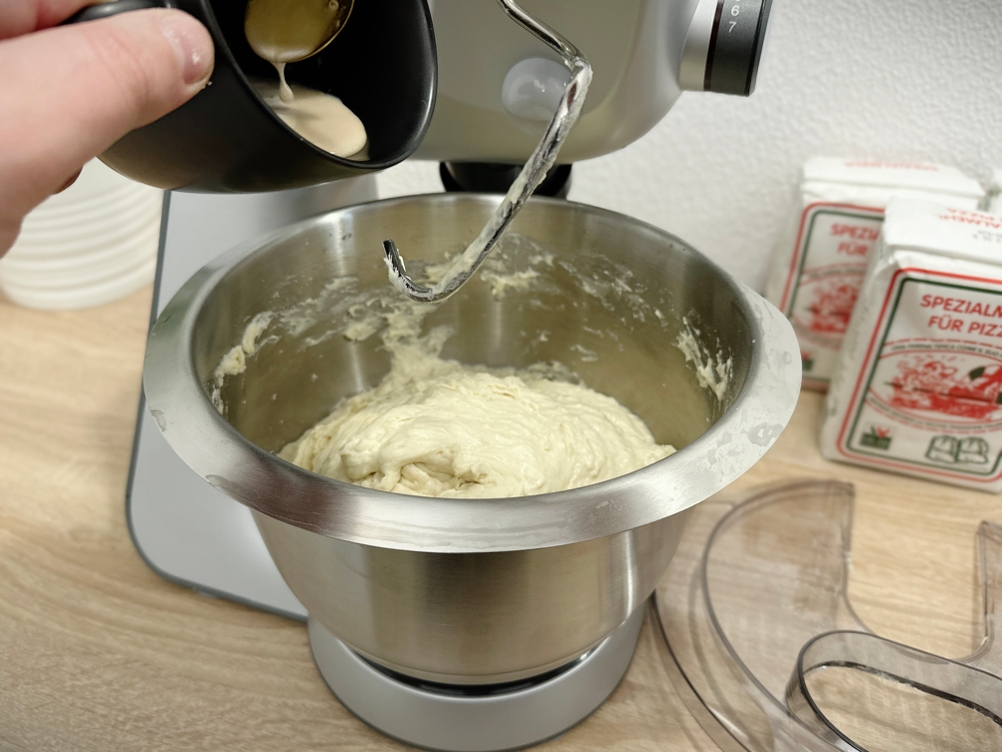 Zucker wird in den Teig in der Rührschüssel der Bosch MUM56340 gegeben. Der Knethaken ist bereits eingesetzt.