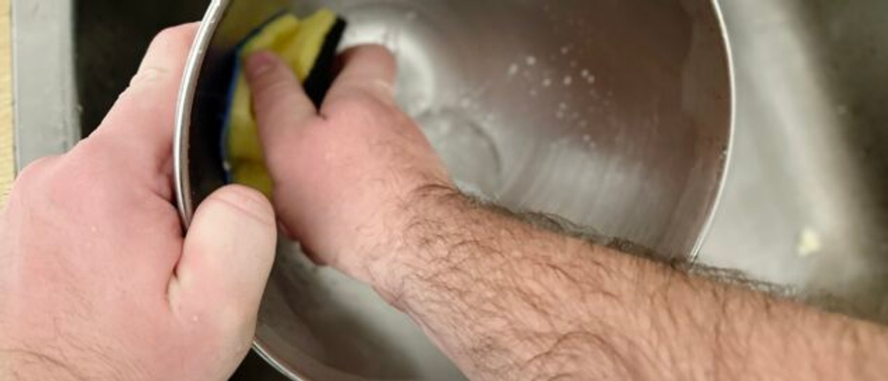 Die Rührschüssel der Küchenmaschine Smeg SMF02PBEU wird per Hand mit einem Schwamm gereinigt. Die Szene zeigt den Reinigungsvorgang über dem Spülbecken.