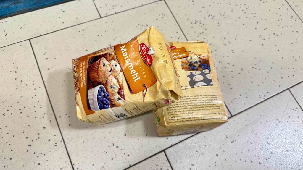 Maismehl im Test: zwei Packungen von Küchenmeister, Vorder- und Rückansicht, liegen auf einem Fliesenbelag.