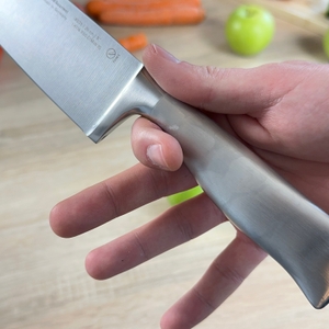 Der Griff des WMF-Grand-Gourmet-Messers wird mit feuchten Fingern gehalten. Es sind leichte Schweißreste zu sehen.