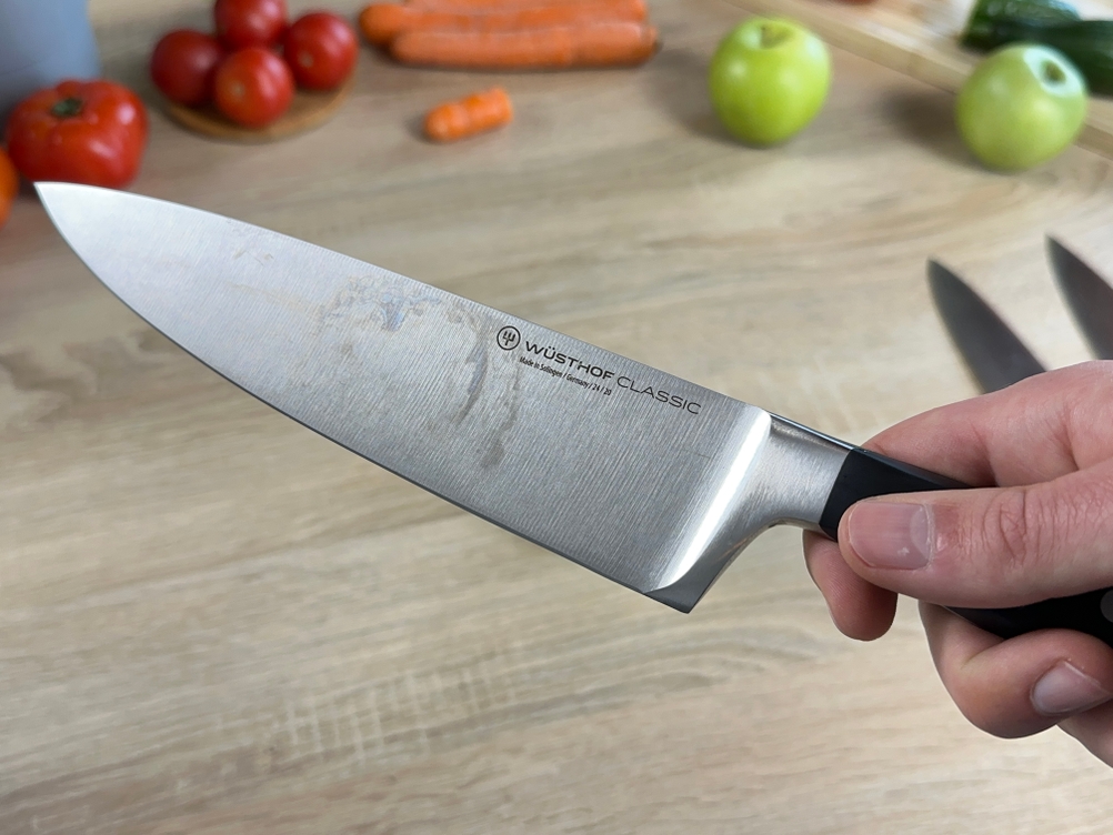 Ein Wüsthof-Chefmesser wird nach dem Spülen in der Hand gehalten. Die Klinge zeigt leichte Wasserflecken.