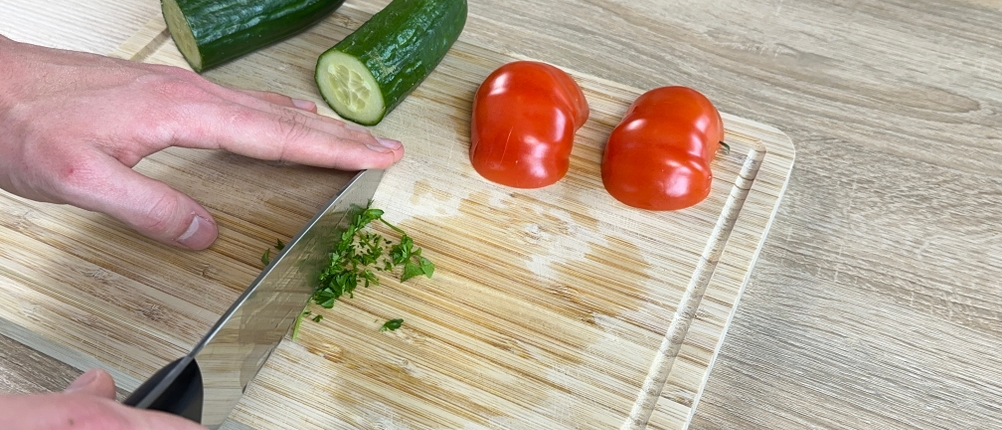 Das Messer von Zwilling schneidet Petersilie auf einem Schneidebrett.