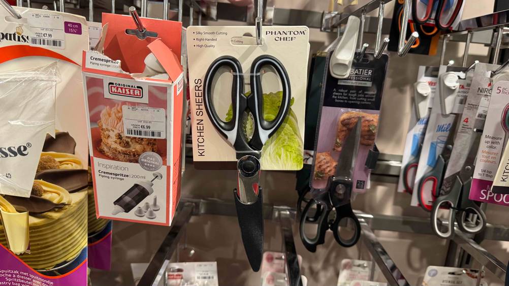 Eine getestete Küchenschere hängt neben anderen Produkten in einem Regal.