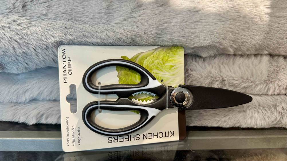 Eine Küchenschere im Test horizontal vor einer Kuscheldecke.