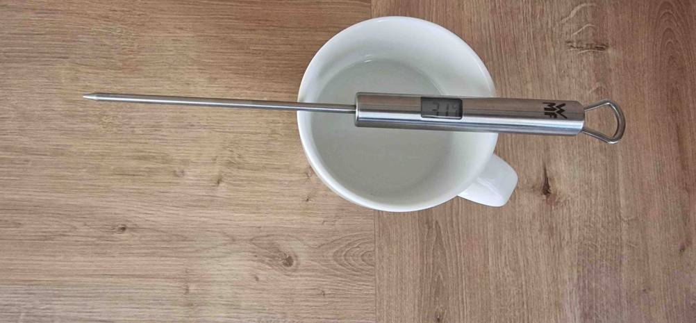 Auf einer Tasse befindet sich ein getestetes Küchenthermometer für Flüssigkeiten.