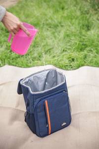 Kühlrucksäcke getestet: Jemand gießt mit einem Messbecher Wasser in einen Kühlrucksack.