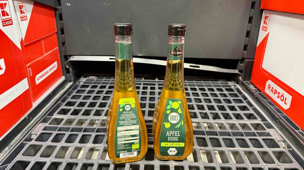 Bio-Essig im Test: Eine Flasche steht mir der Rückseite nach vorn neben einer zweiten auf einem Gitter.