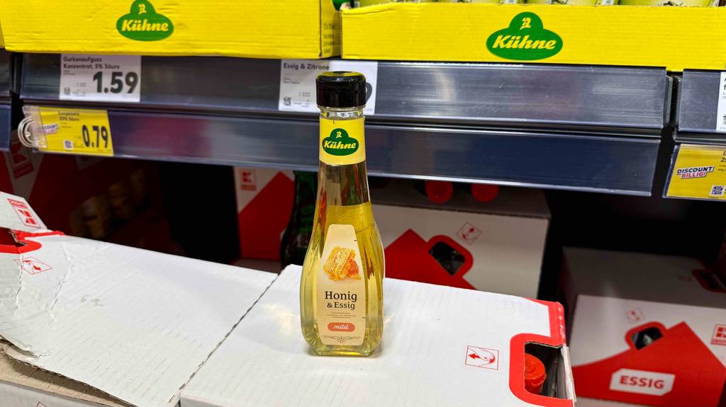 Eine Flasche Honig-Essig steht zum Testen auf einem Karton vor einem Verkaufsregal.