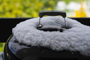 Kugelgrilldeckel ist mit Schnee bedeckt.