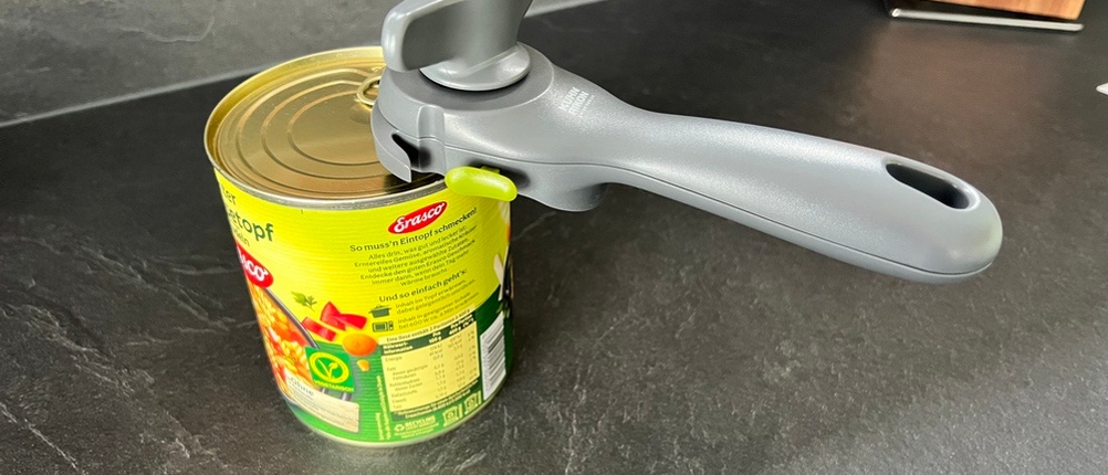 Dosenöffner hängt an einer Dose, weil er fest eingerastet ist