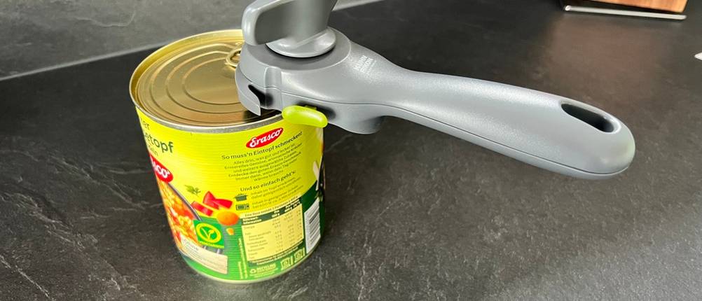 Dosenöffner hängt an einer Dose, weil er fest eingerastet ist