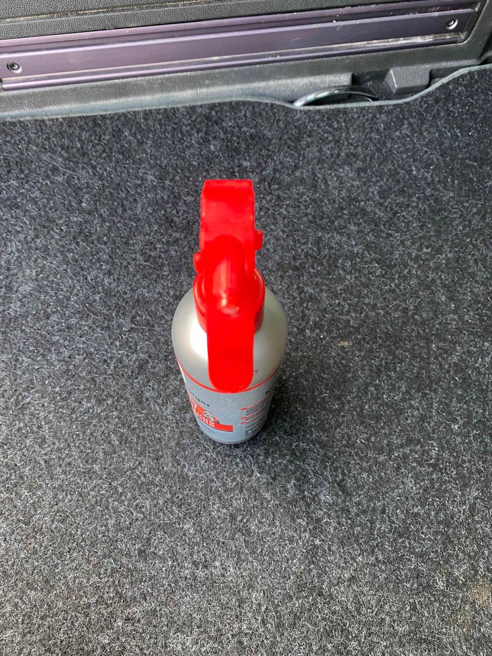 Nahaufnahme des Sprühkopfes einer Flasche des getesteten Kunststoffreinigers von oben auf einem grauen Teppich.