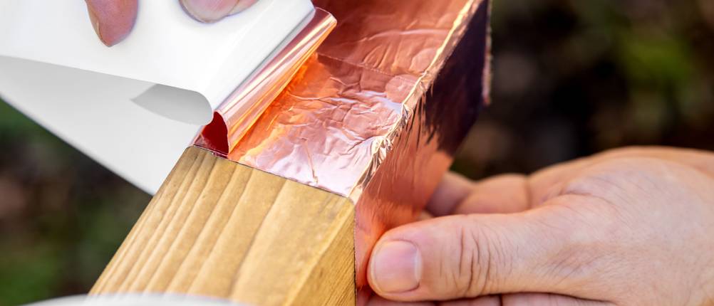 Kupferband-Test: Mann klebt Kupferband um Holz