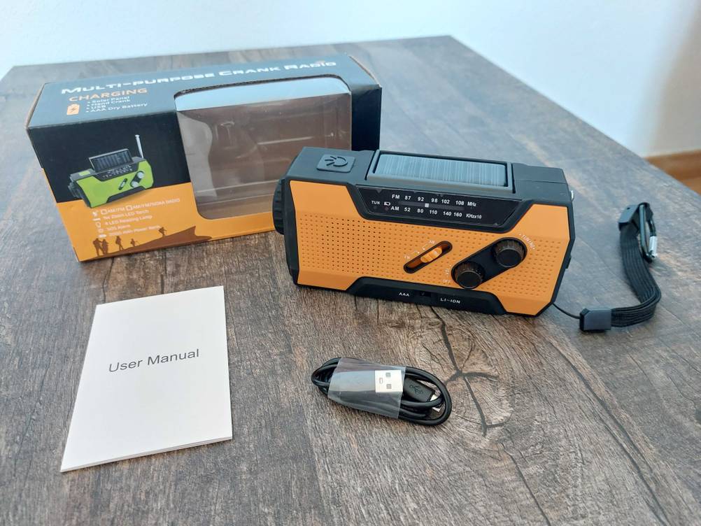 Kurbelradio getestet: Ein Radio mit Originalverpackung und Zubehör auf einem dunklen Tisch.