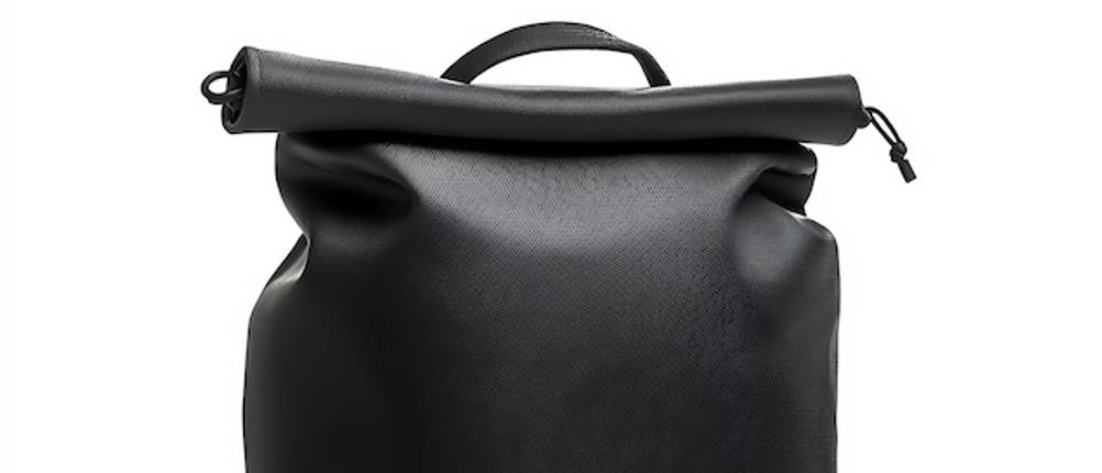 Kurier-Rucksack-Test: Rolltop-Verschluss eines schwarzen Kurier-Rucksacks in Nahaufnahme vor einem weißen Hintergrund.