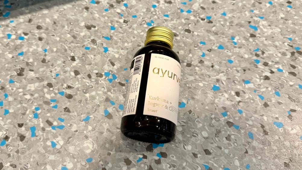 Kurkuma flüssig im Test: Eine Flasche von schräg unten auf einem Boden liegend.