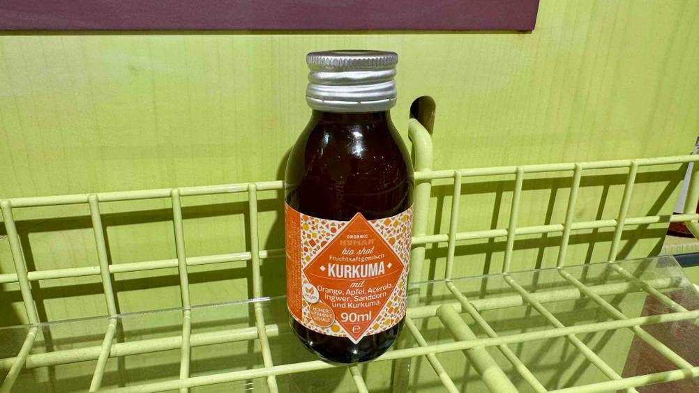 Der getestete Kurkuma-Shot auf einem grünen Gitterregal.