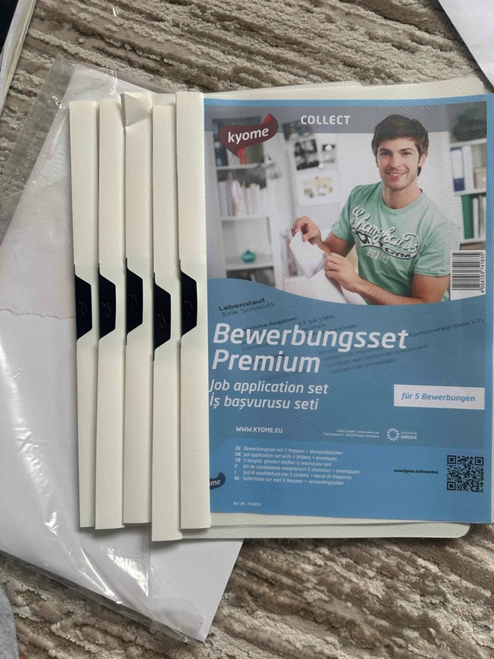Mehrere getestete Bewerbungsmappen liegen übereinander auf einem hellen Stoff.