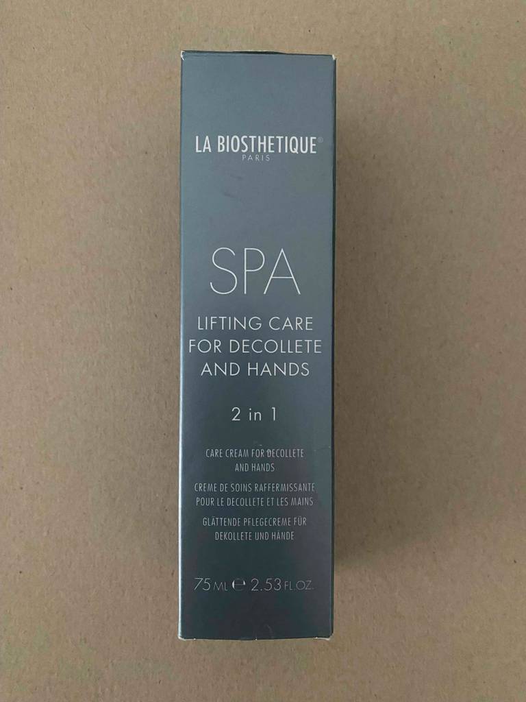 Eine graue Verpackung der getesteten Dekolleté-Creme liegt auf einem braunen Untergrund.