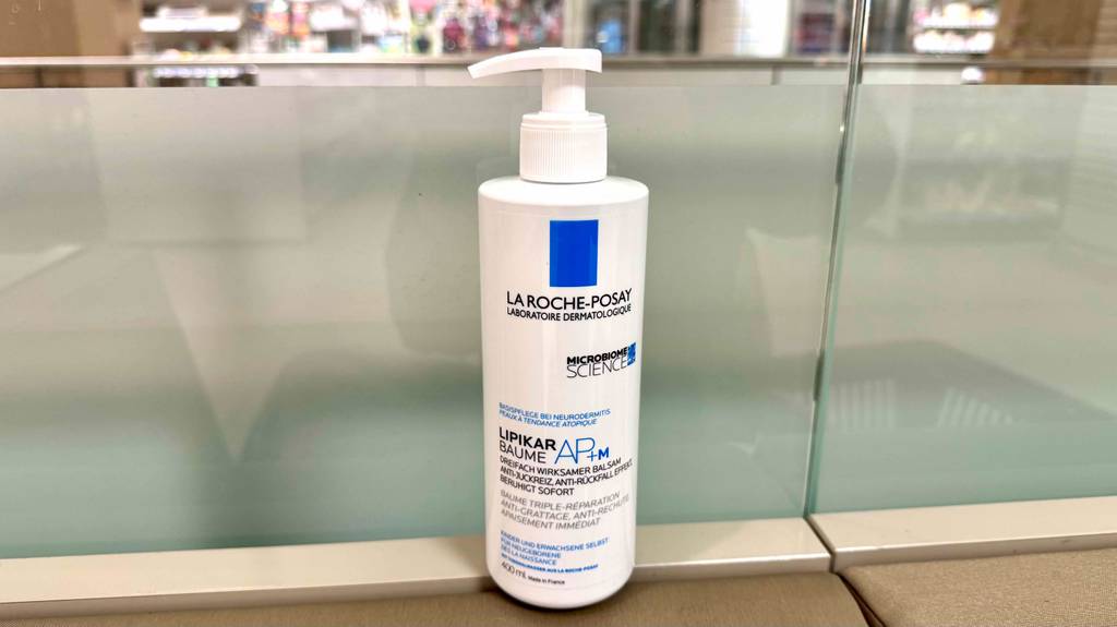 Eine Spenderflasche La Roche Posay Bodylotion steht zum testen vor einer Glaswand.
