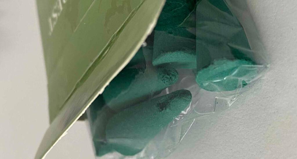 Räucherkerzen-Test: Grüne Räucher-Kegel liegen in Zellophan verpackt auf einer weißen Oberfläche.