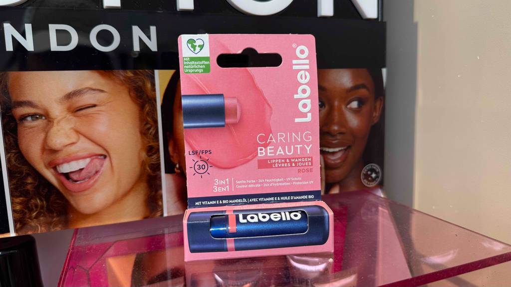 Im Test: Lippenpflege mit Farbe steht in der Verpackung auf einem Regal.