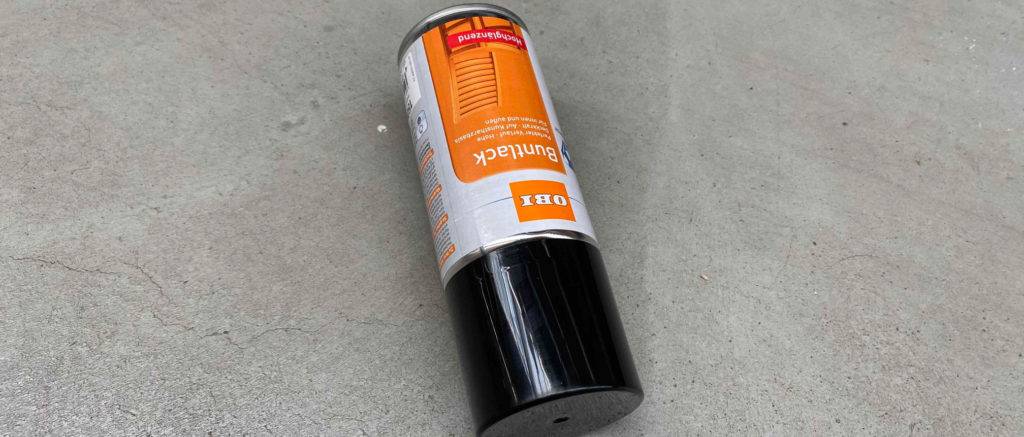 Das getestete Lackspray liegt auf einer grauen Unterlage.