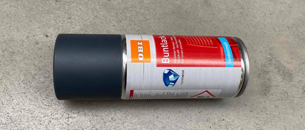 Das getestete Lackspray liegt auf einem grauen Untergrund.