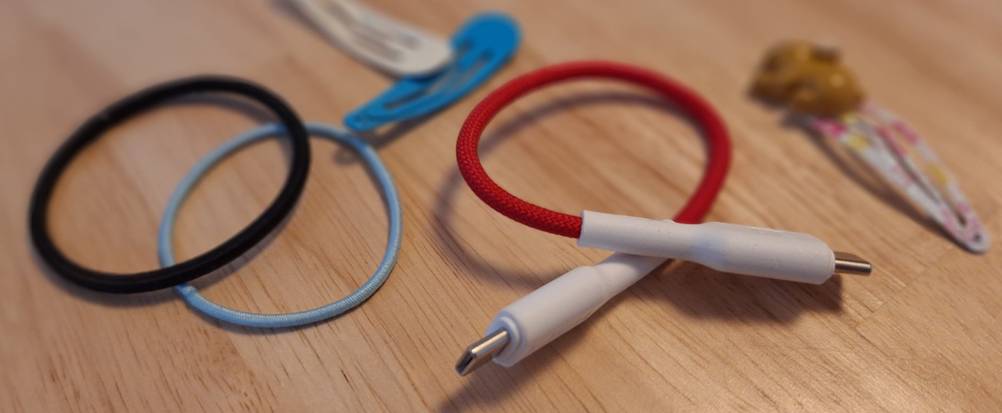 Das USB-C-Ladekabel der Toniebox neben zwei Haargummis und zwei Haarspangen.
