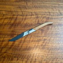 Ein Laguiole-Style-de-Vie-Steakmesser Luxury Line liegt auf einem Holztisch