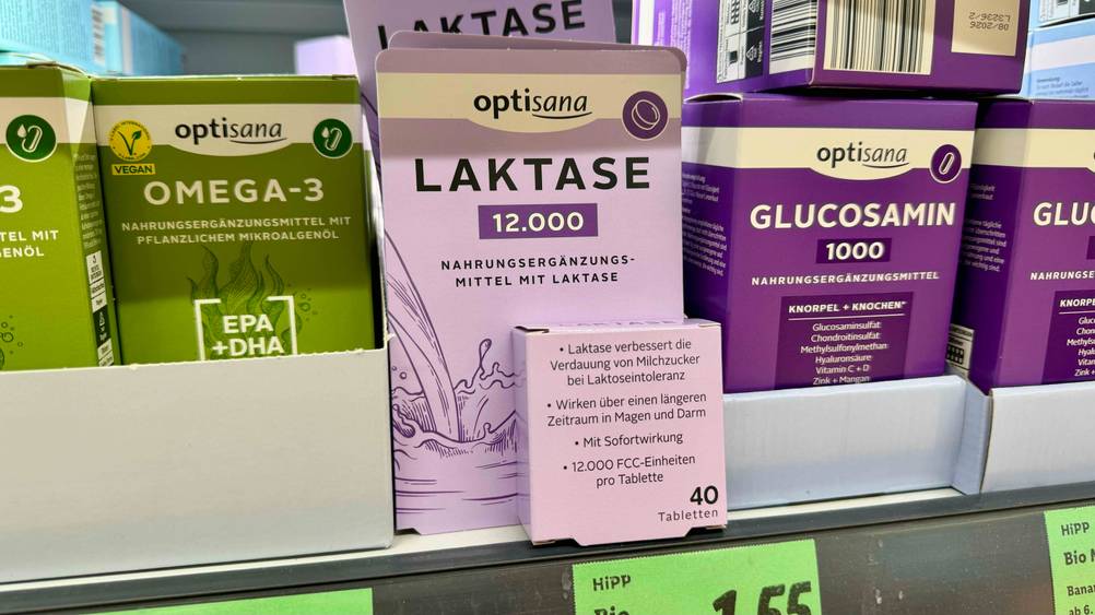 Laktase-Tabletten getestet: Mehrere Packungen stehen hintereinander in einem Regal neben anderen Produkten.
