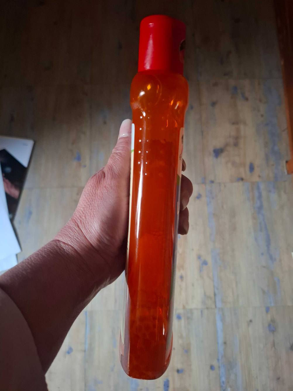 Eine Hand hält die Flasche der getesteten Laminatpflege seitlich hoch.