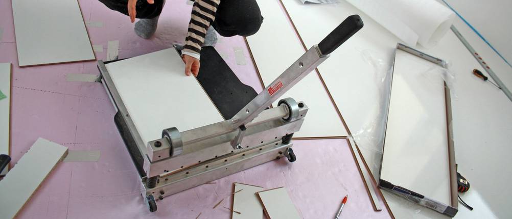 Mann nutzt einen Laminatschneider mit Schneidklinge.